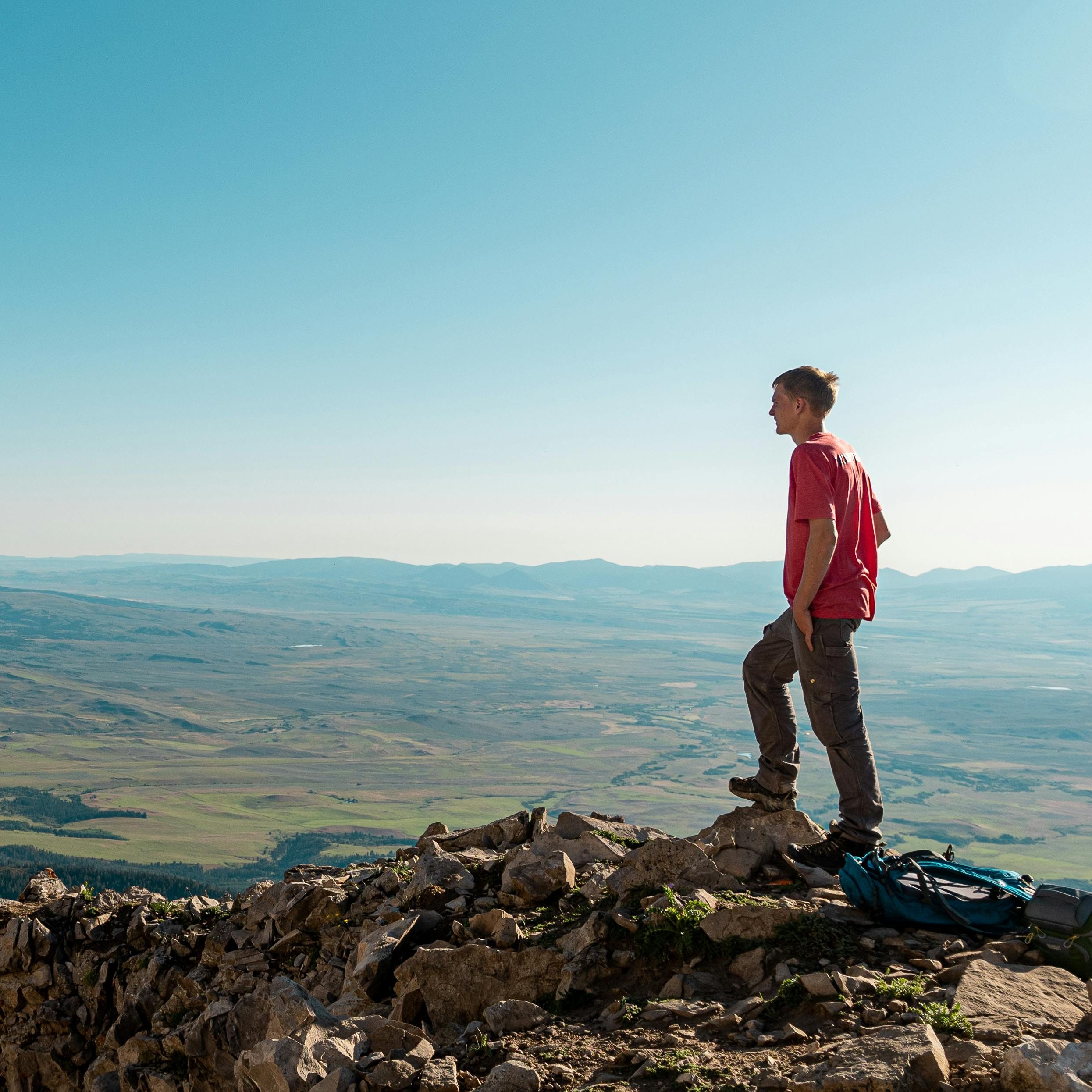 A young man on a hike on the top of a mountain.
